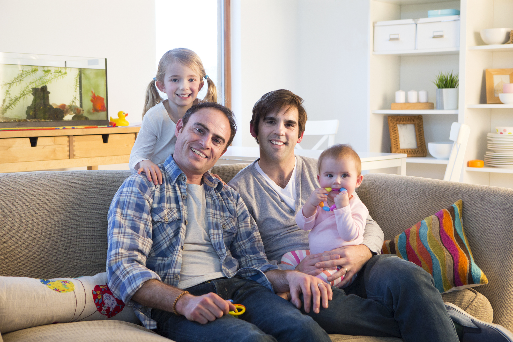 Woman and man sitting on couch with two small children smiling